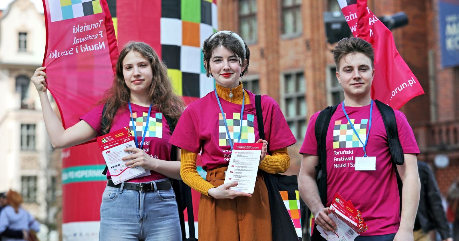 Hasłem przewodnim tegorocznej edycji Toruńskiego Festiwalu Nauki i Sztuki jest OTWARTOŚĆ Młodzi ludzie stoją w różowych koszulkach
