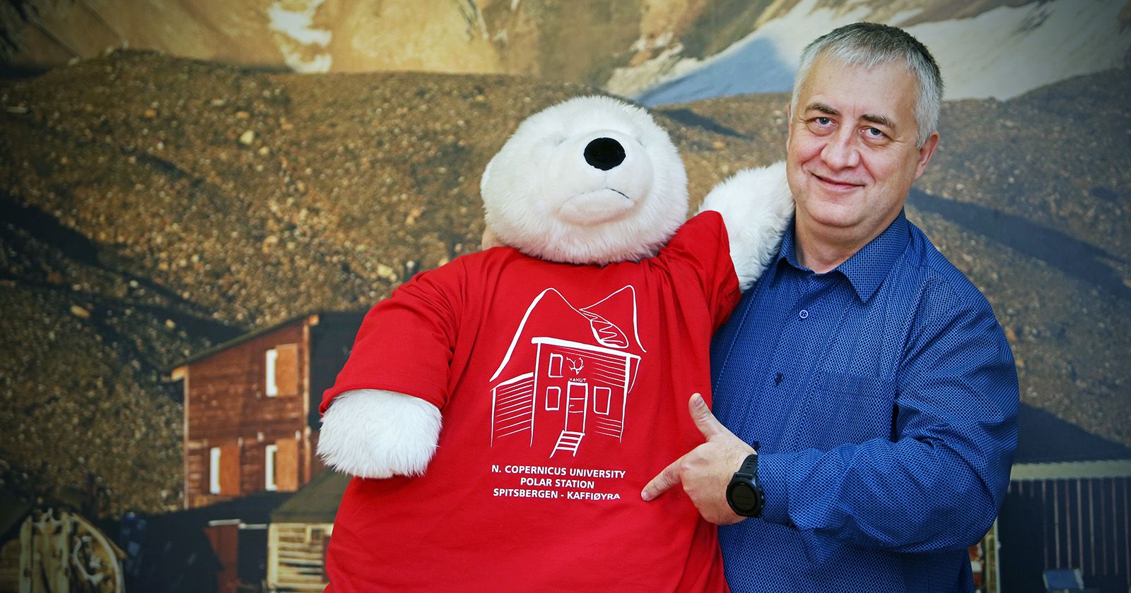 Dr hab. Ireneusz Sobota, prof. UMK Prof. Sobota pozuje do zdjęcia z dużym pluszowym niedźwiedziem w koszulce z grafiką Stacji Polarnej UMK