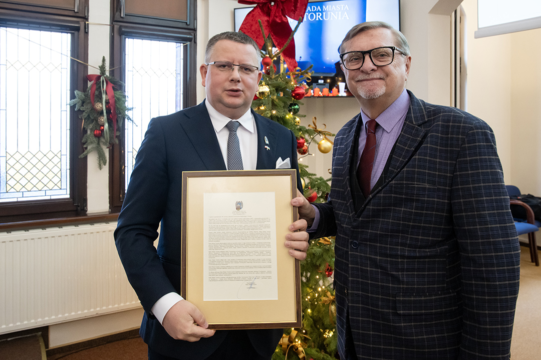 Szef Rady Miasta Łukasz Walkusz trzyma w ręku wydruk stanowiska rady miasta, obok stoi prof. Andrzej Radzimiński