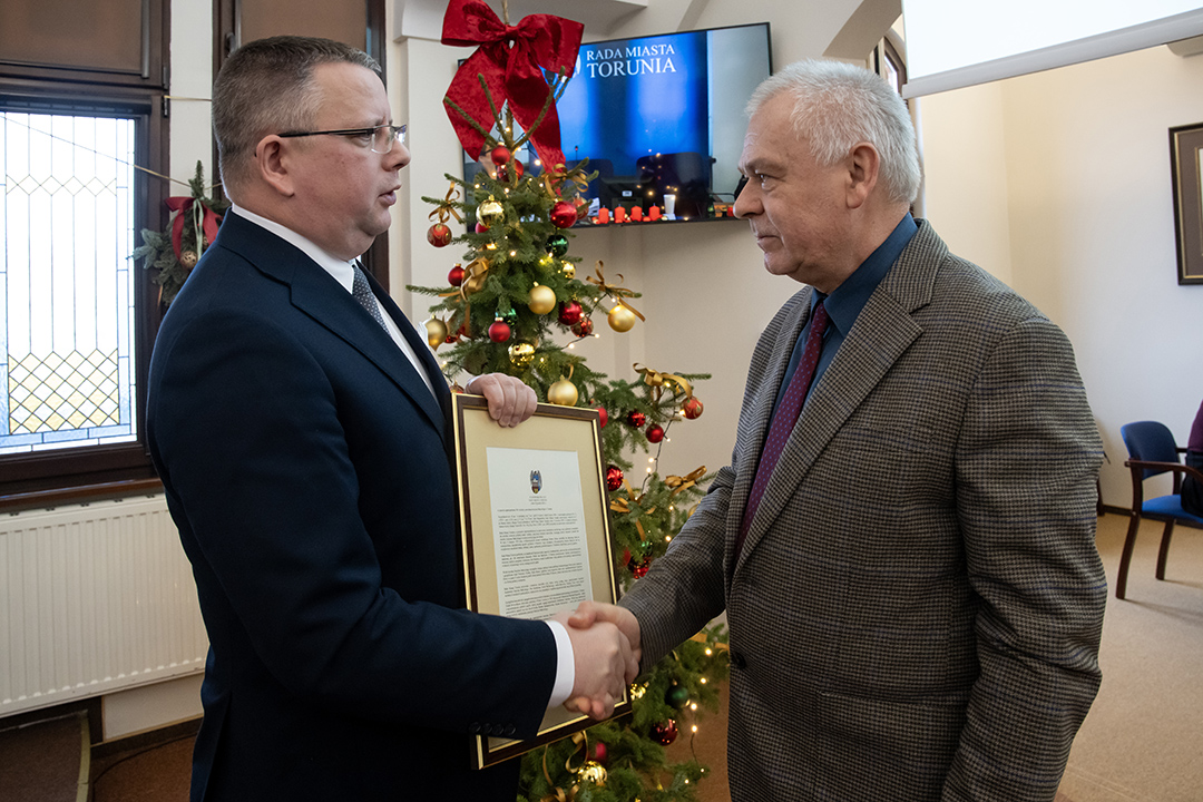 Dr hab. Jacek Gackowski, prof. UMK odbiera od Łukasza Walkusza oprawiony wydruk stanowiska rady miasta