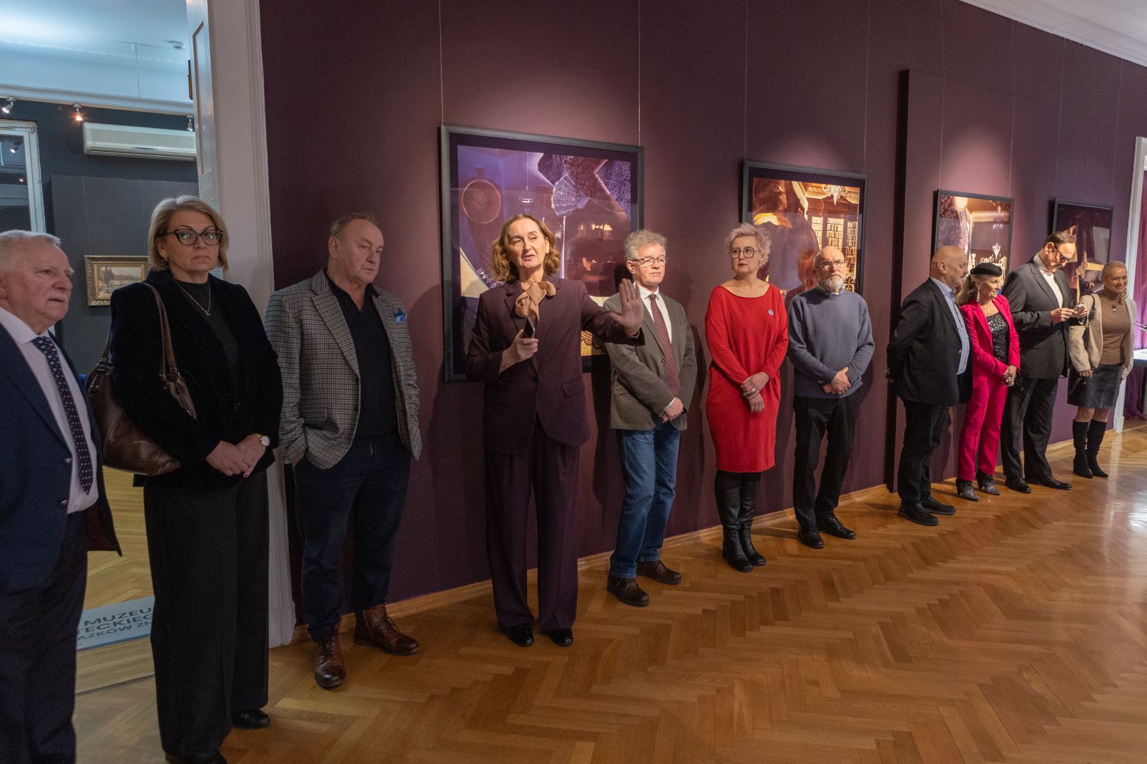 Kobiety i mężczyźni elgencka ubrani stoją pod ścianą z obrazami