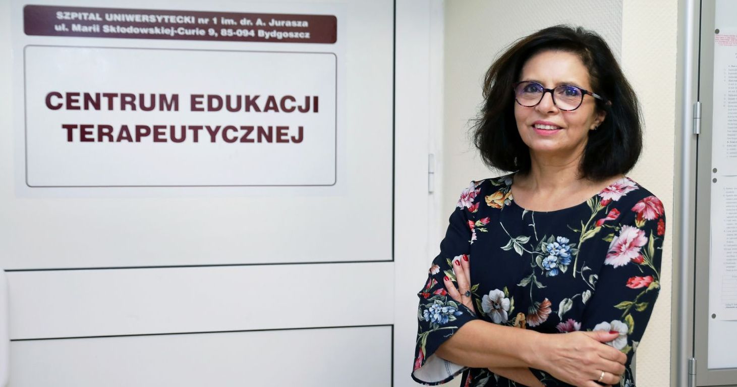 Prof. dr hab. Aldona Kubica Prof. dr hab. Aldona Kubica stoi przy drzwiach z napisem "Centrum edukacji terapeutycznej"