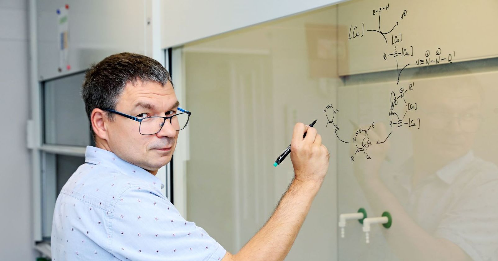 Dr Mariusz Bosiak z Katedry Chemii Organicznej przy tablic z wzorem chemicznym