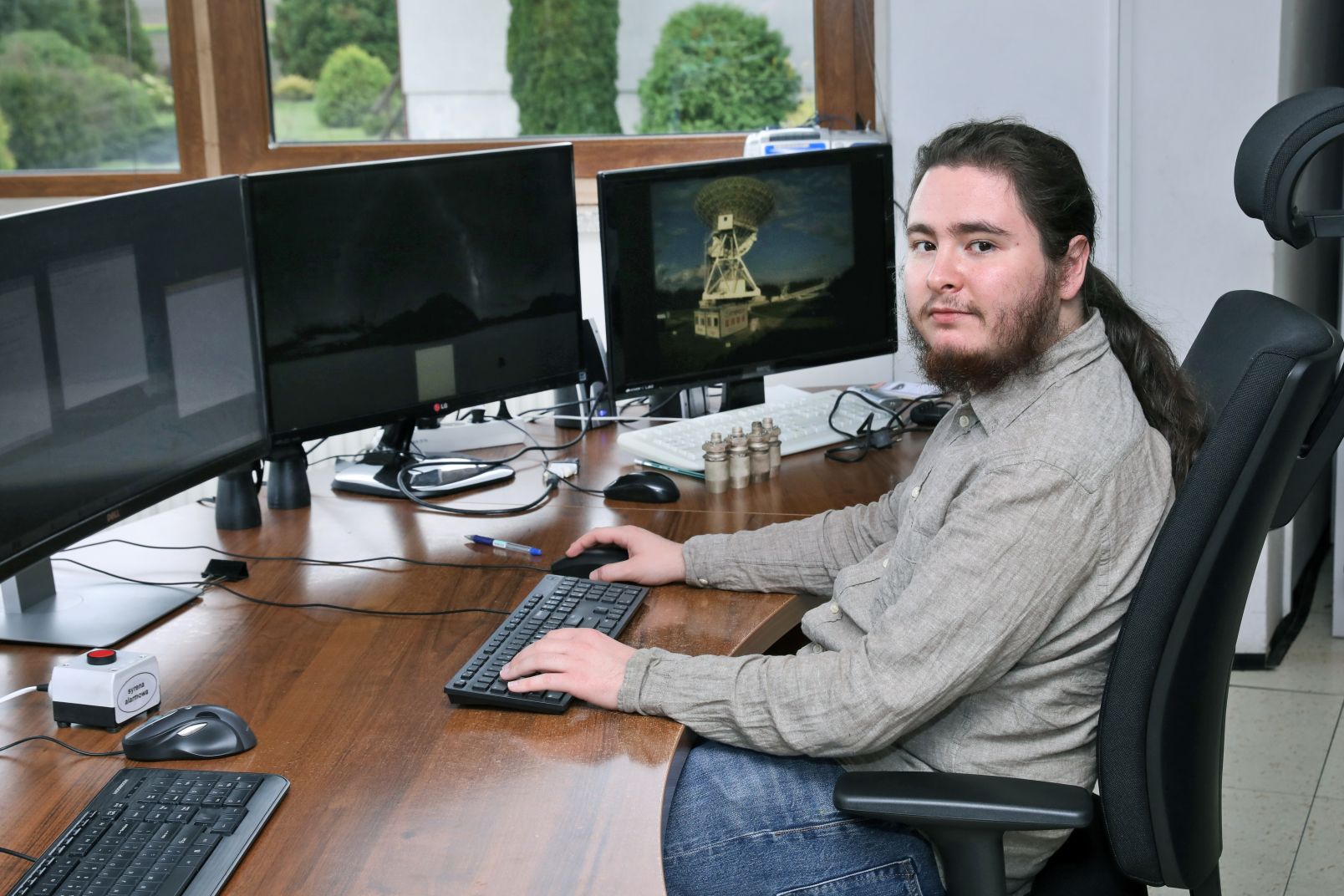 Mężczyzna siedzi przy biurku, na którym stoi monitor