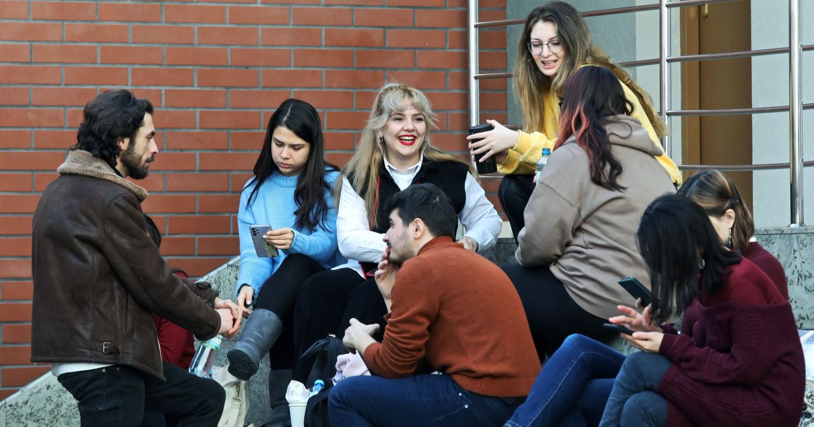 Rekrutacja do Programu Mobilności Studentów i Doktorantów ruszyła 15 kwietnia Grupa studentów i studentek siedzi na schodach i rozmawia ze sobą. Na zdjęciu jest osiem osób.