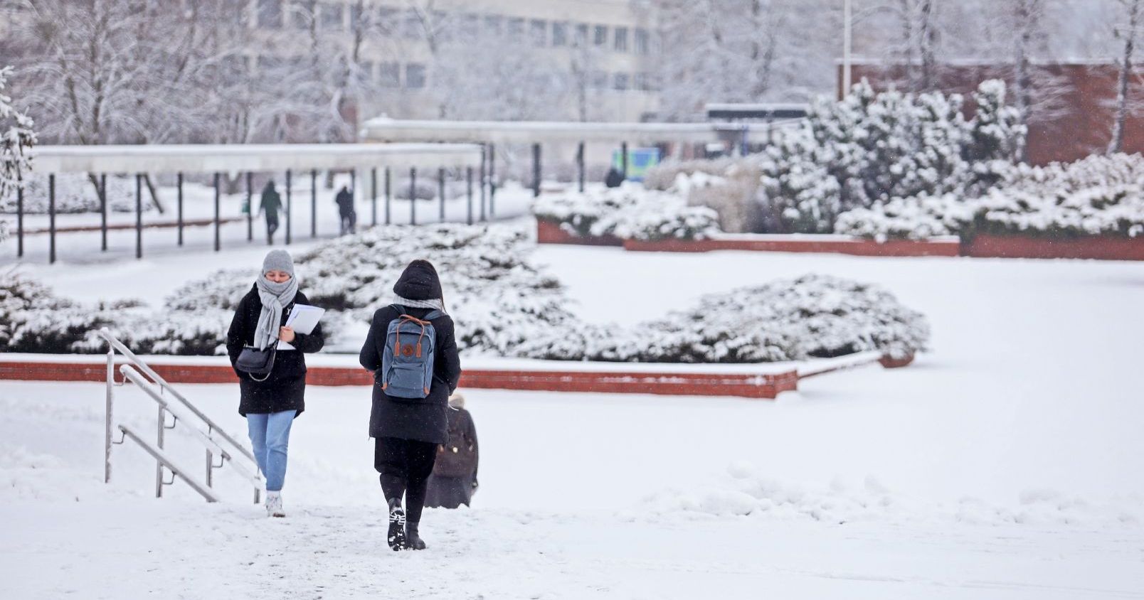  Zimowy krajobraz miasteczka uniwersyteckiego, śnieg, na zdjęciu dwie osoby idące po chodniku