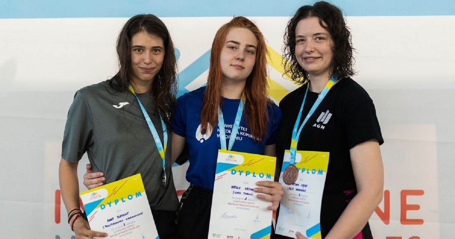 Natalia Krymow (na środku) Zdjęcie przedstawia trzy kobiety, które stoją obok siebie. Na szyi mają medale, a w dłoniach trzymają dyplomy. W środku Natalia Krymow.