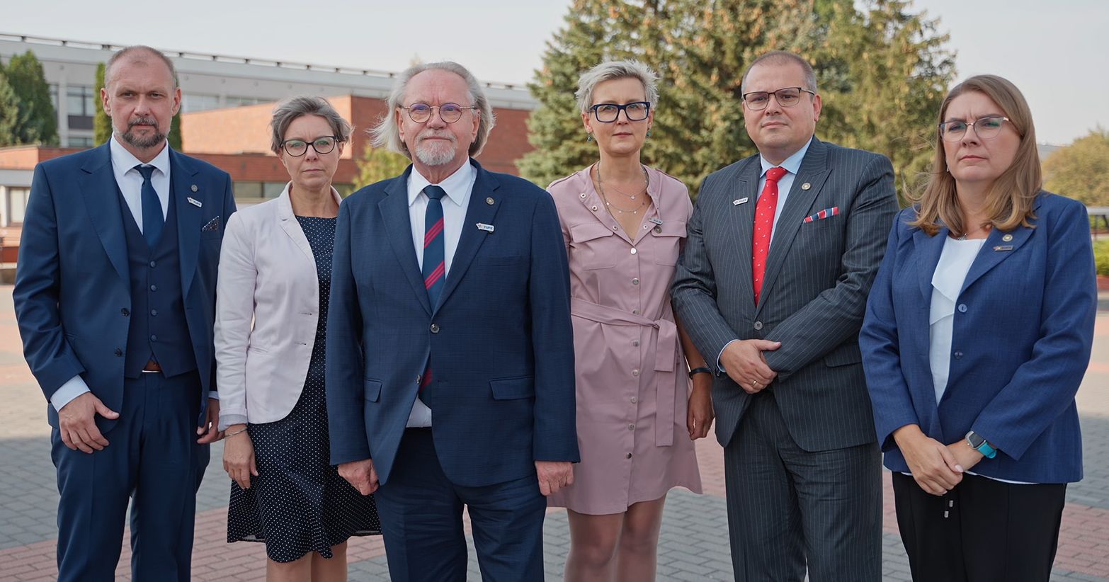  Członkowie Kolegium Rektorskiego UMK stoją na kampusie uniwersyteckim.