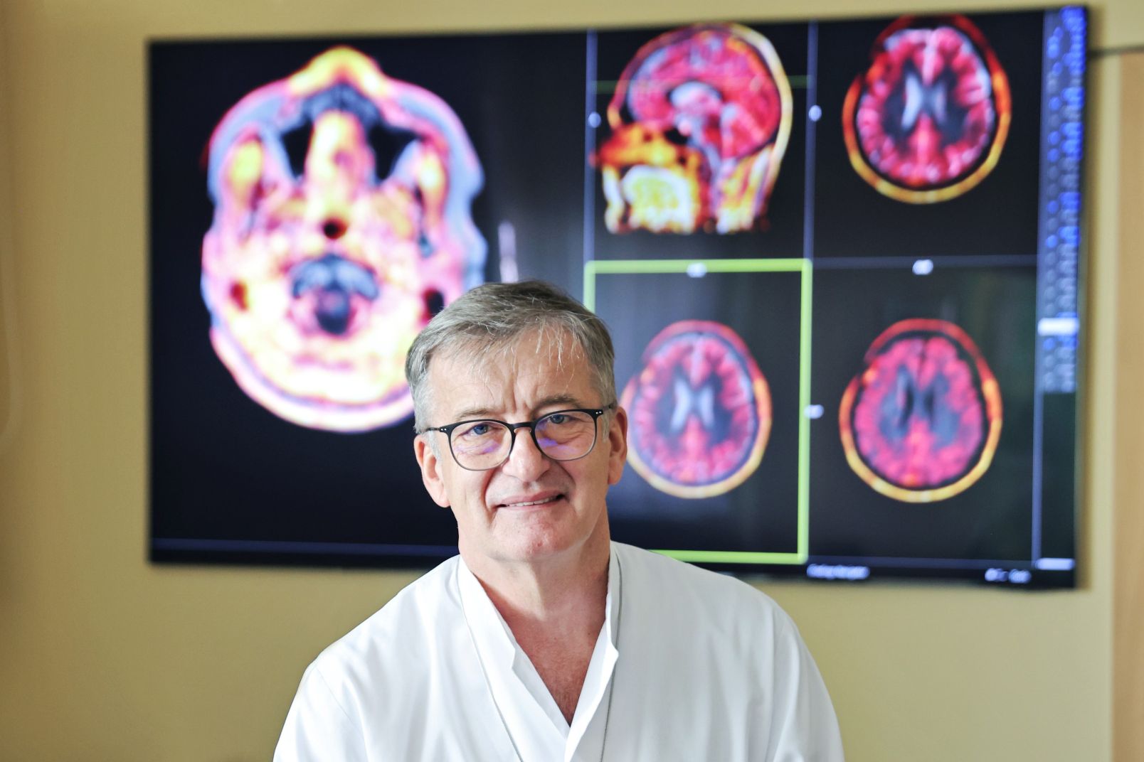 Duży monitor z kolorowymi obrazami mózgu przy którym stoi dr hab. Bogdan Małkowski, prof. UMK