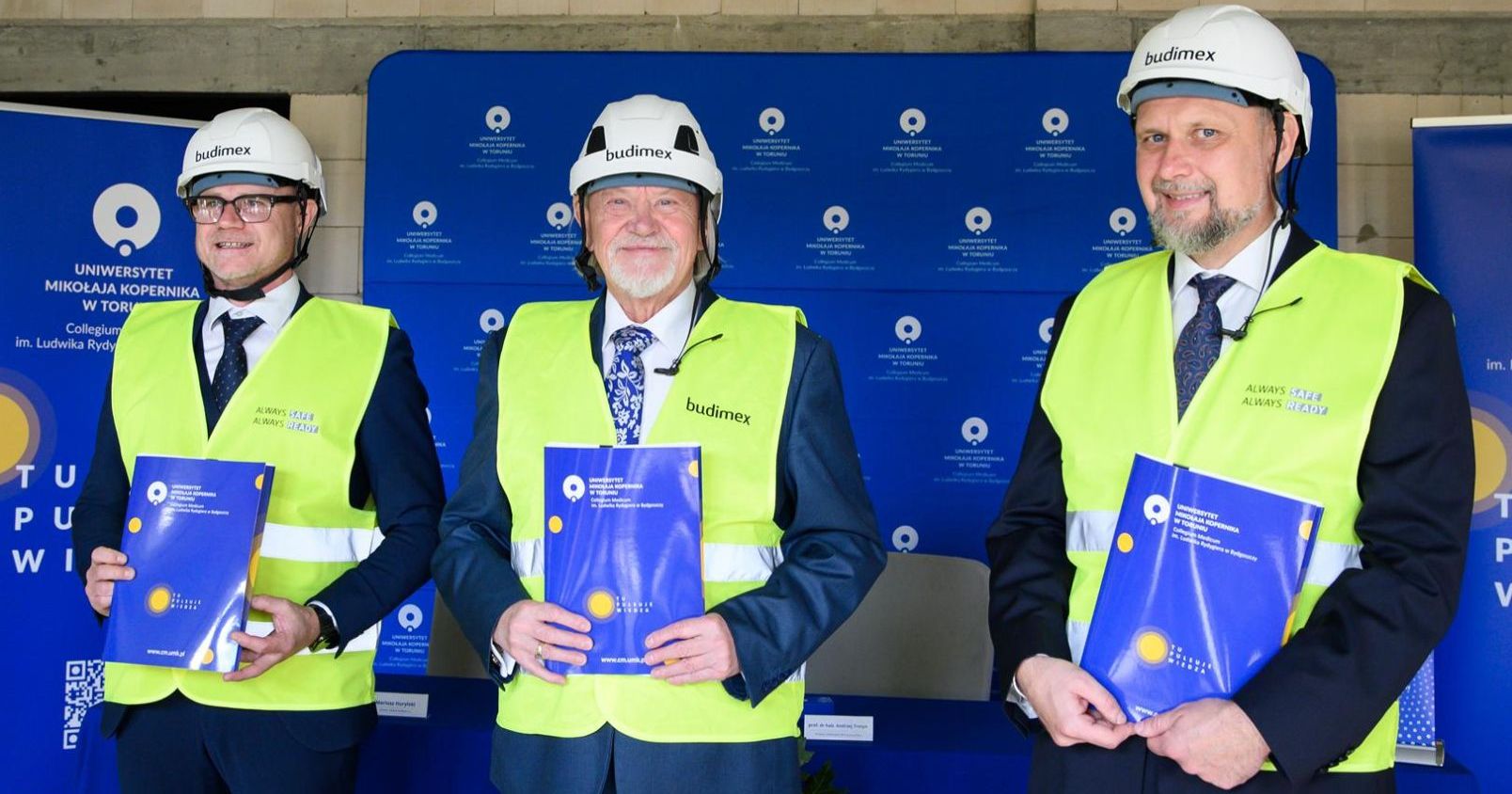 Standing with blue folders in their hands, from left to right: Mariusz Hurylski, Branch Director of BUDIMEX S.A, prof. Andrzej Tretyn, NCU Rector prof. Dariusz Grzanka, Vice-Rector for Collegium Medicum