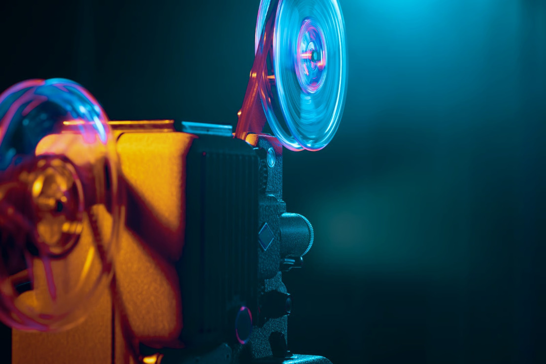 Stary projektor filmowy z rolkami taśm w złoto-turkusowym świetle