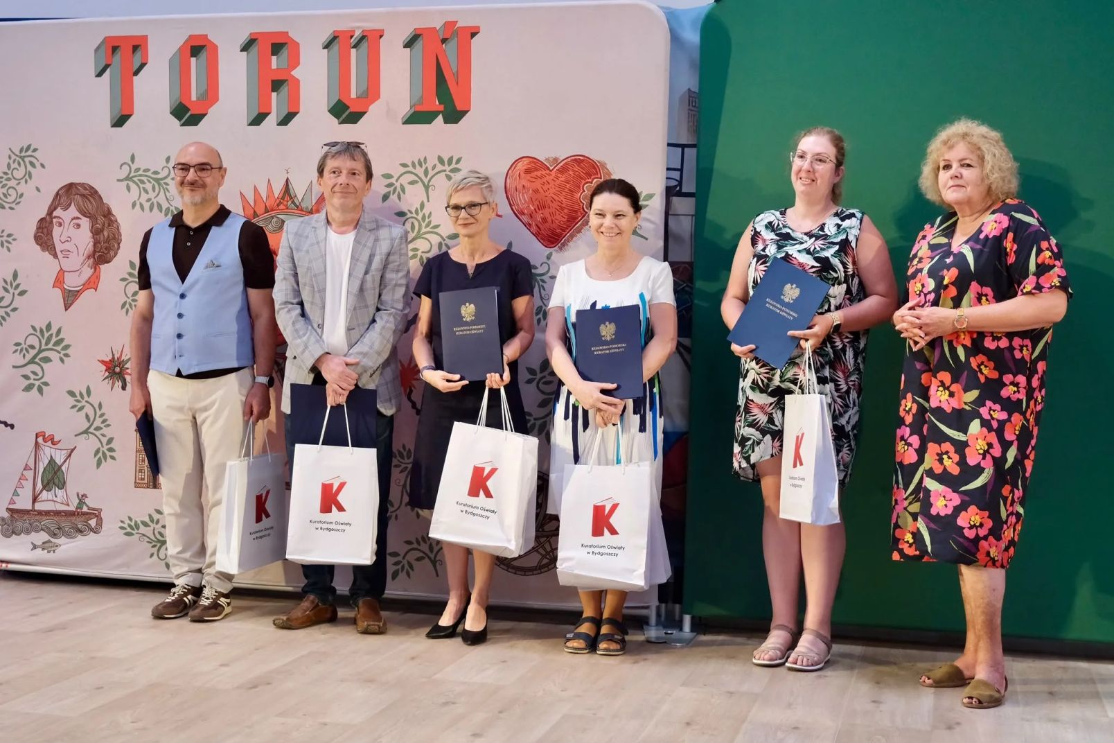 Nauczyciele ULO z nagrodami i listami gratulacyjnymi pozują do wsp&oacute;lnego zdjęcia z wicekurator oświaty