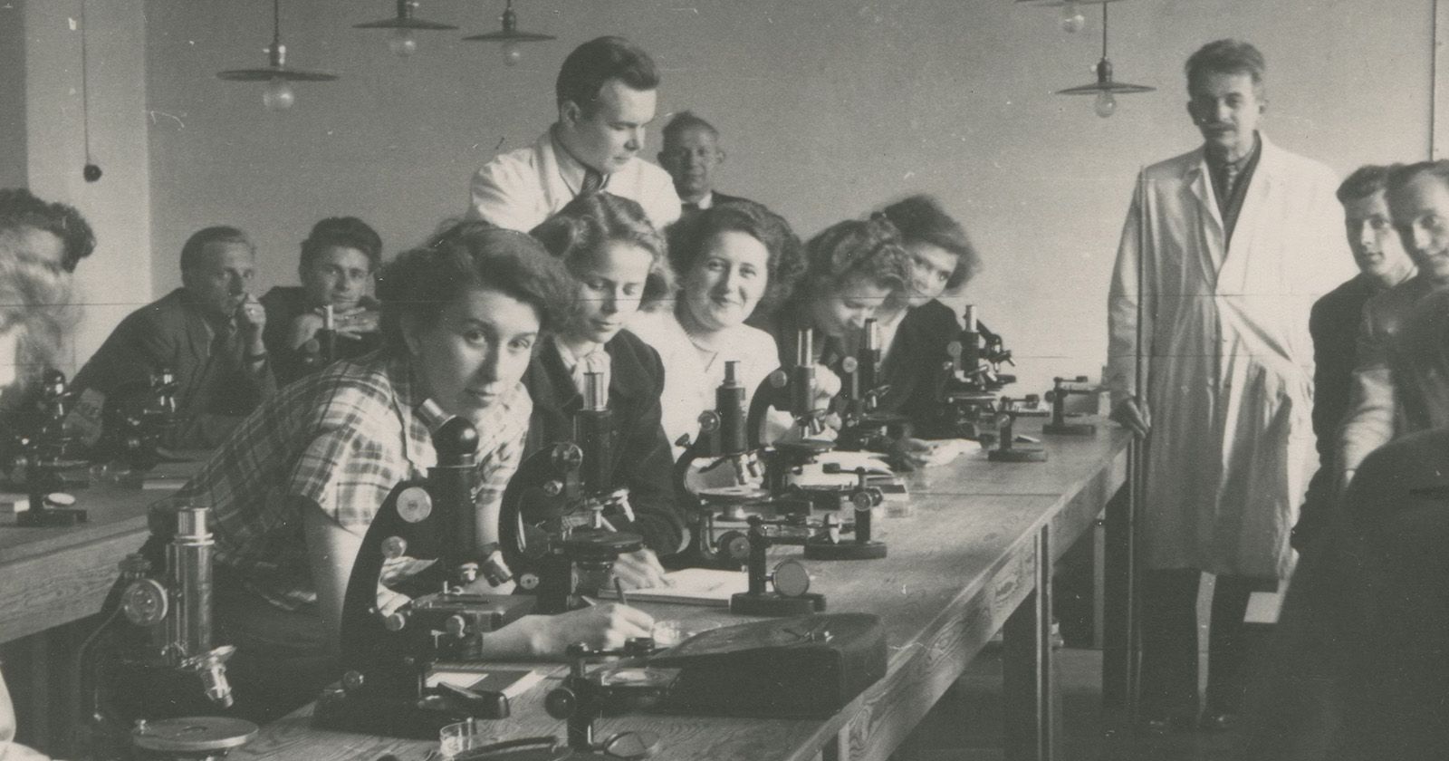 W roku akademickim 1945/1946 na studia na Uniwersytecie Mikołaja Kopernika w Toruniu zapisało się 1605 osób Czarno-biała fotografia pierwszych studentów UMK przy mikroskopach w sali laboratoryjnej