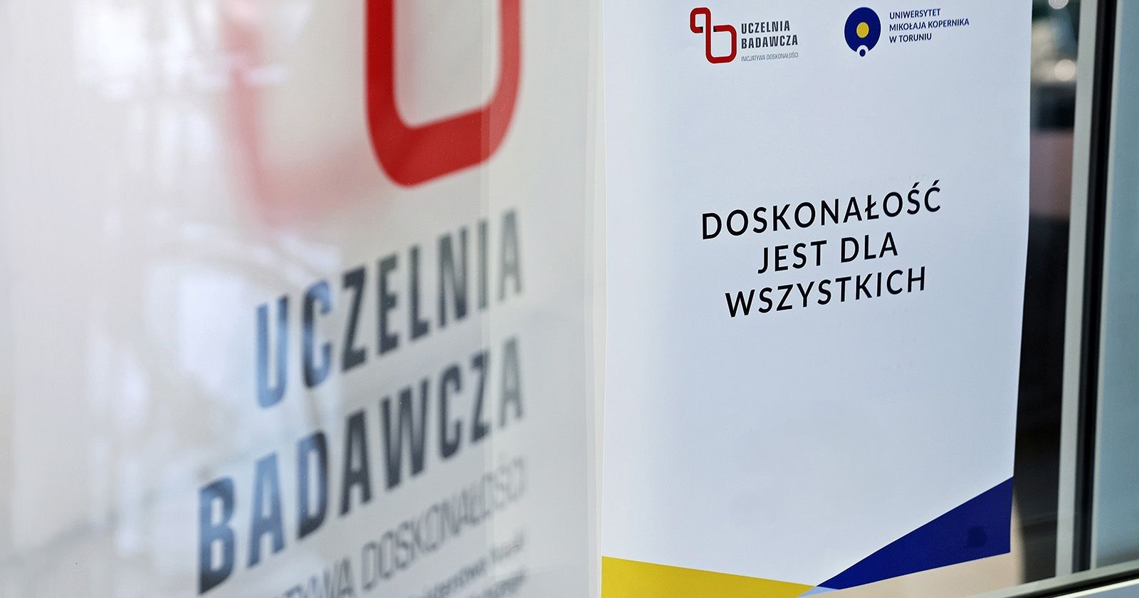 Wydarzenie będzie doskonałą okazją do poznania liderów zespołów, które tworzą Priorytetowe Obszary Badawcze, nawiązania kontaktów i wymiany doświadczeń Zdjęcie roll-upu z napisem Uczelnia Badawcza i drugiego z napisem Doskonałość jest dla wszystkich