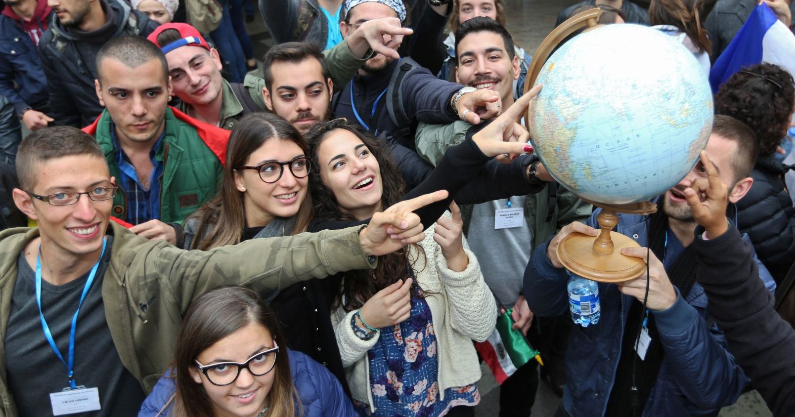 A group of people point with their fingers on globe