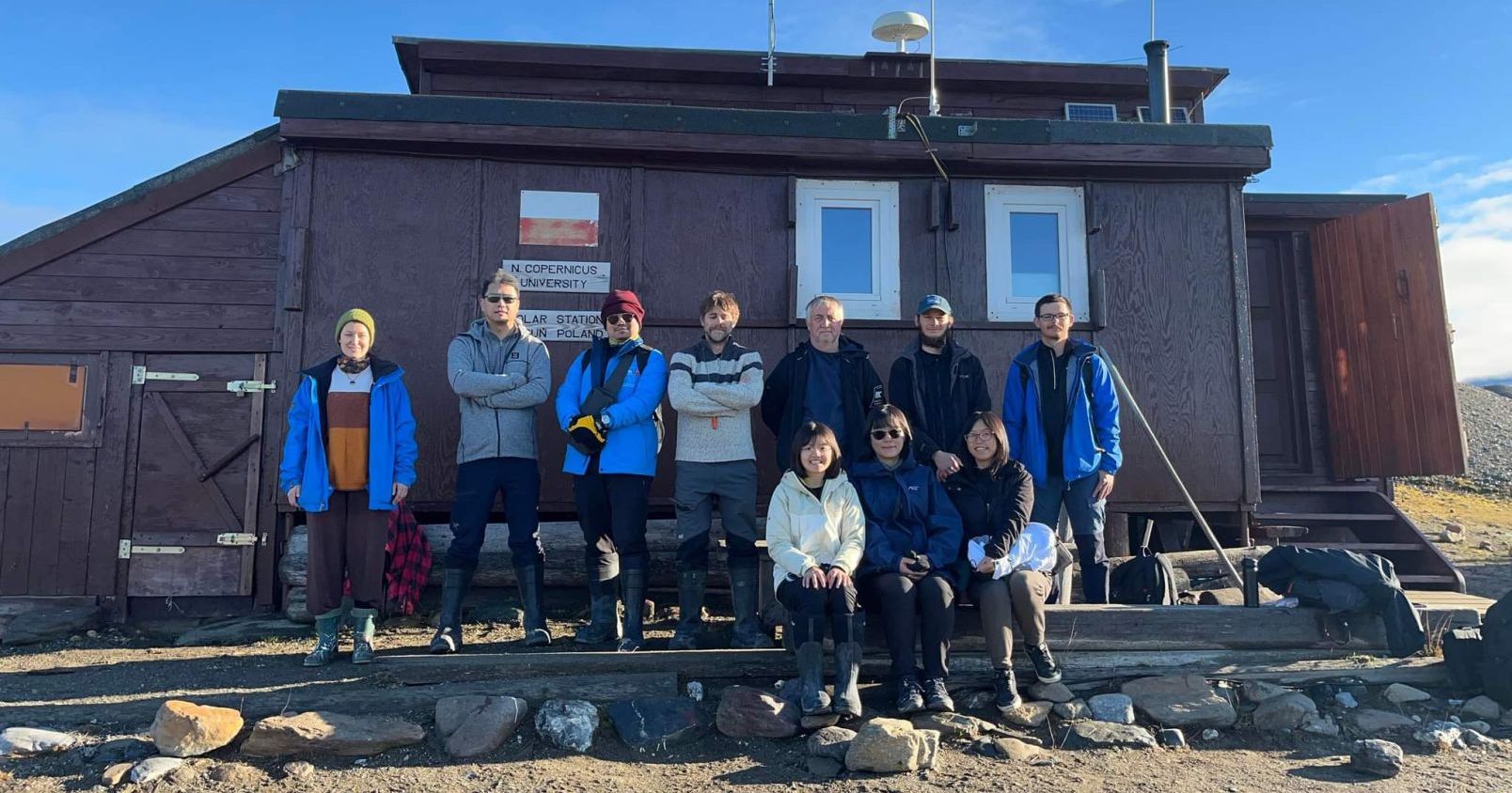 W ekspedycji trwającej od połowy czerwca do początku września 2022 r. wzięły udział 22 osoby. Na zdjęciu znajduje się grupa 10 osób, pozująca przed budynkiem Stacji Polarnej UMK na Spitsbergenie.