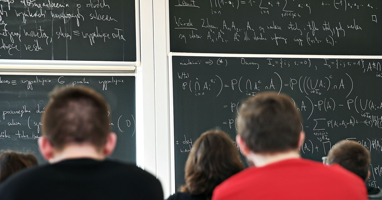  Studenci podczas wykładów przed tablicami, na których zapisano obliczenia