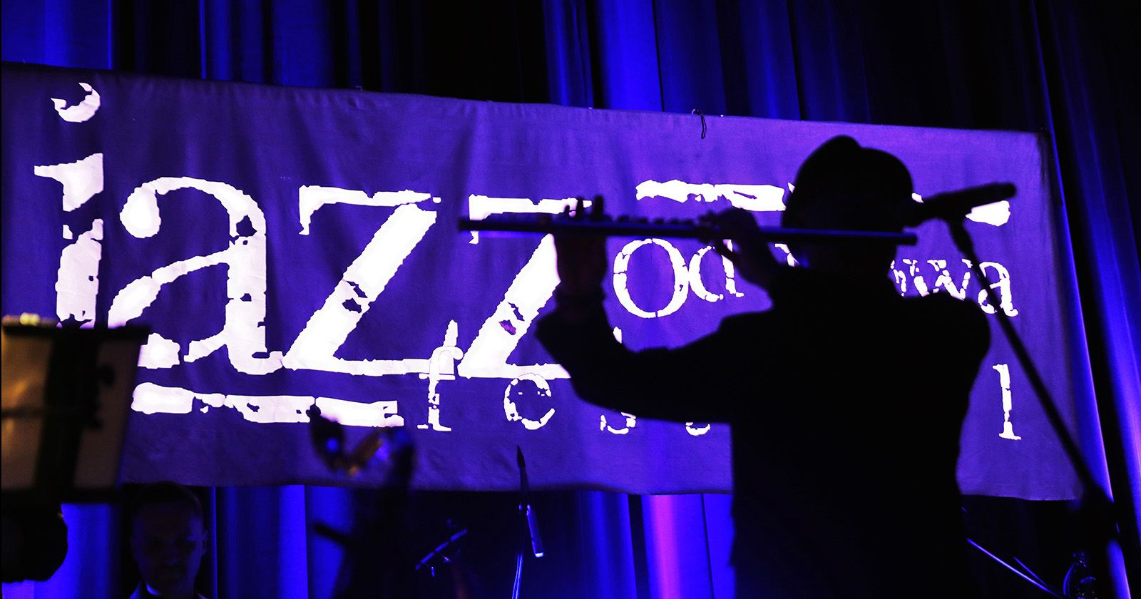 24. edycja JAZZ Od Nowa Festival odbędzie się w dniach 16-19 października Flecista na tle fioletowego banera JAZZ Od Nova Festival