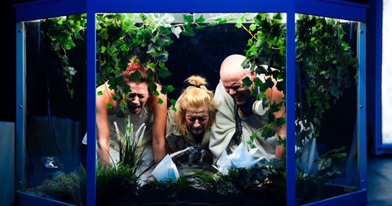 Teatr Kana otworzy tegoroczną KLAMRĘ spektaklem pt. "Światy możliwe" Teatr Kana podczas występu. W dużym akwarium wypełnionym zielonymi roślinami klęczy troje ludzi.
