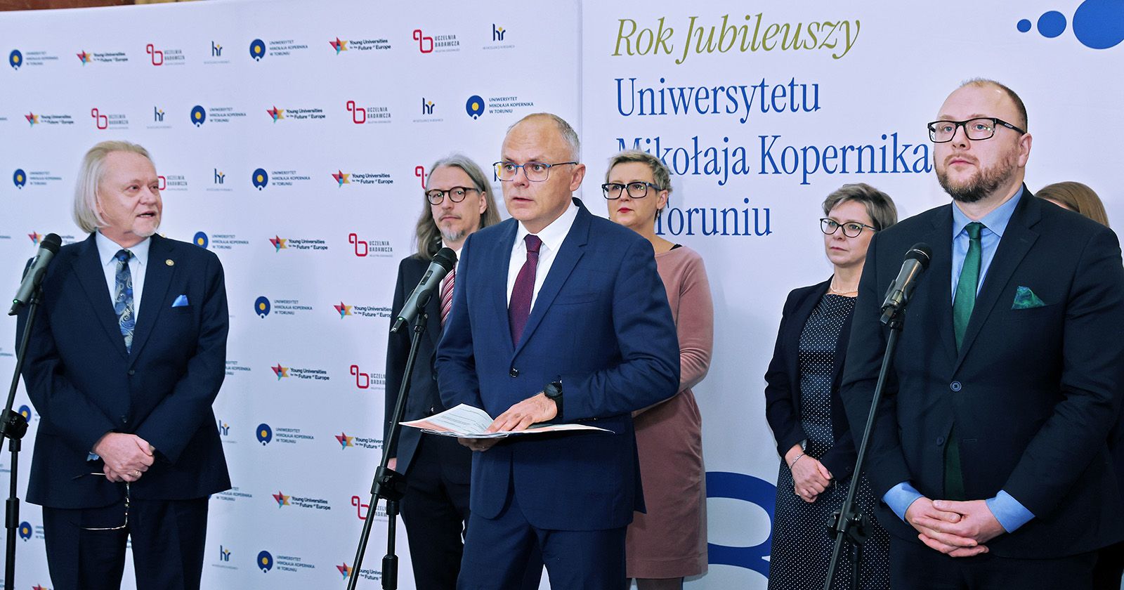 O wysokości przyznanych UMK środków poinformował w poniedziałek Grzegorz Karpiński, zastępca szefa Kancelarii Prezesa Rady Ministrów na wspólnej konferencji prasowej z władzami uczelni i prezydentem Torunia Władze UMK i Torunia na ściance podczas konferencji prasowej