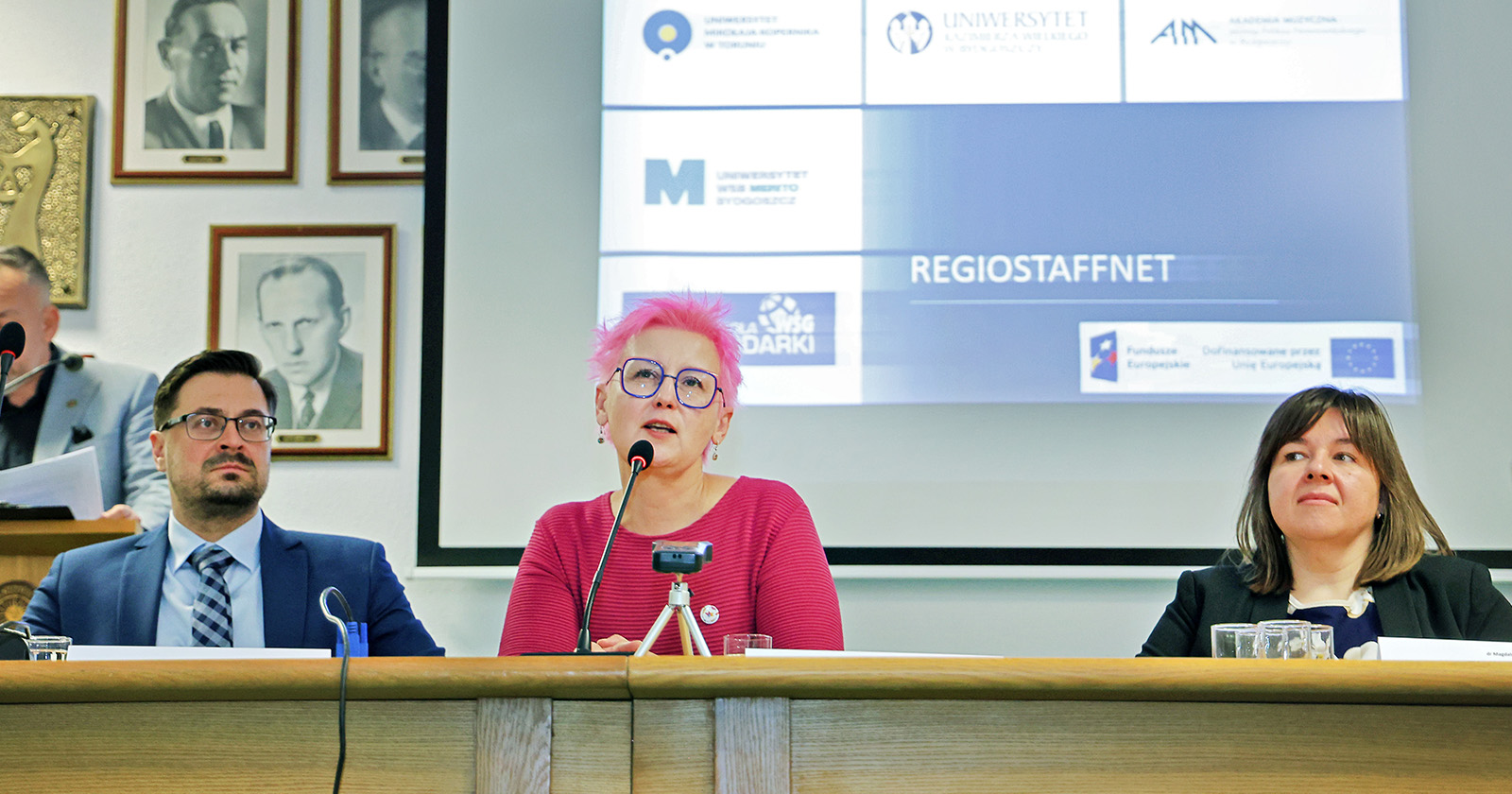 Za stołem przy mikrofonach siedzą trzy osoby. Dwie kobiety i jeden mężczyzna. Trwa konferencja prasowa.