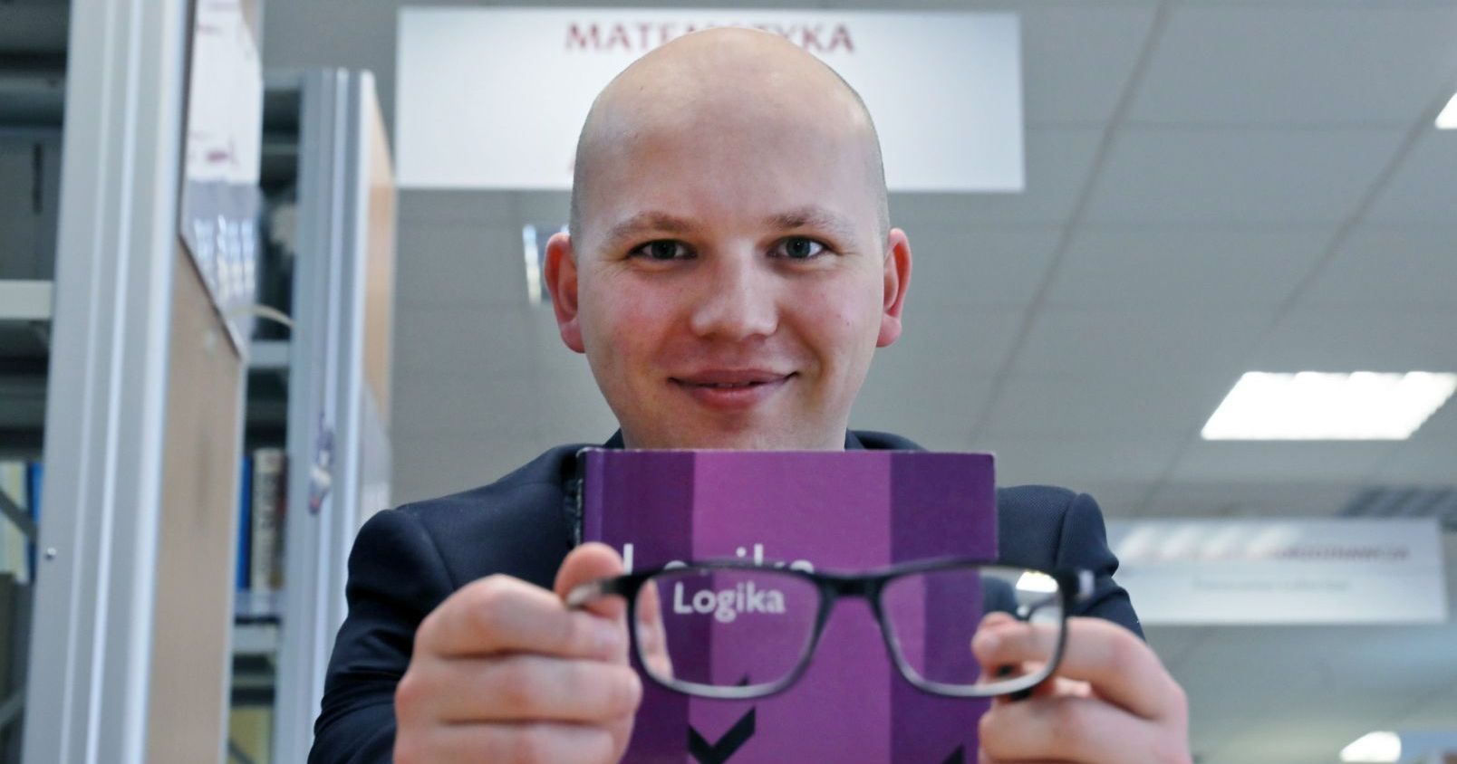 Dr Mateusz Klonowski z Wydziału Filozofii i Nauk Społecznych UMK siedzi w bibliotece