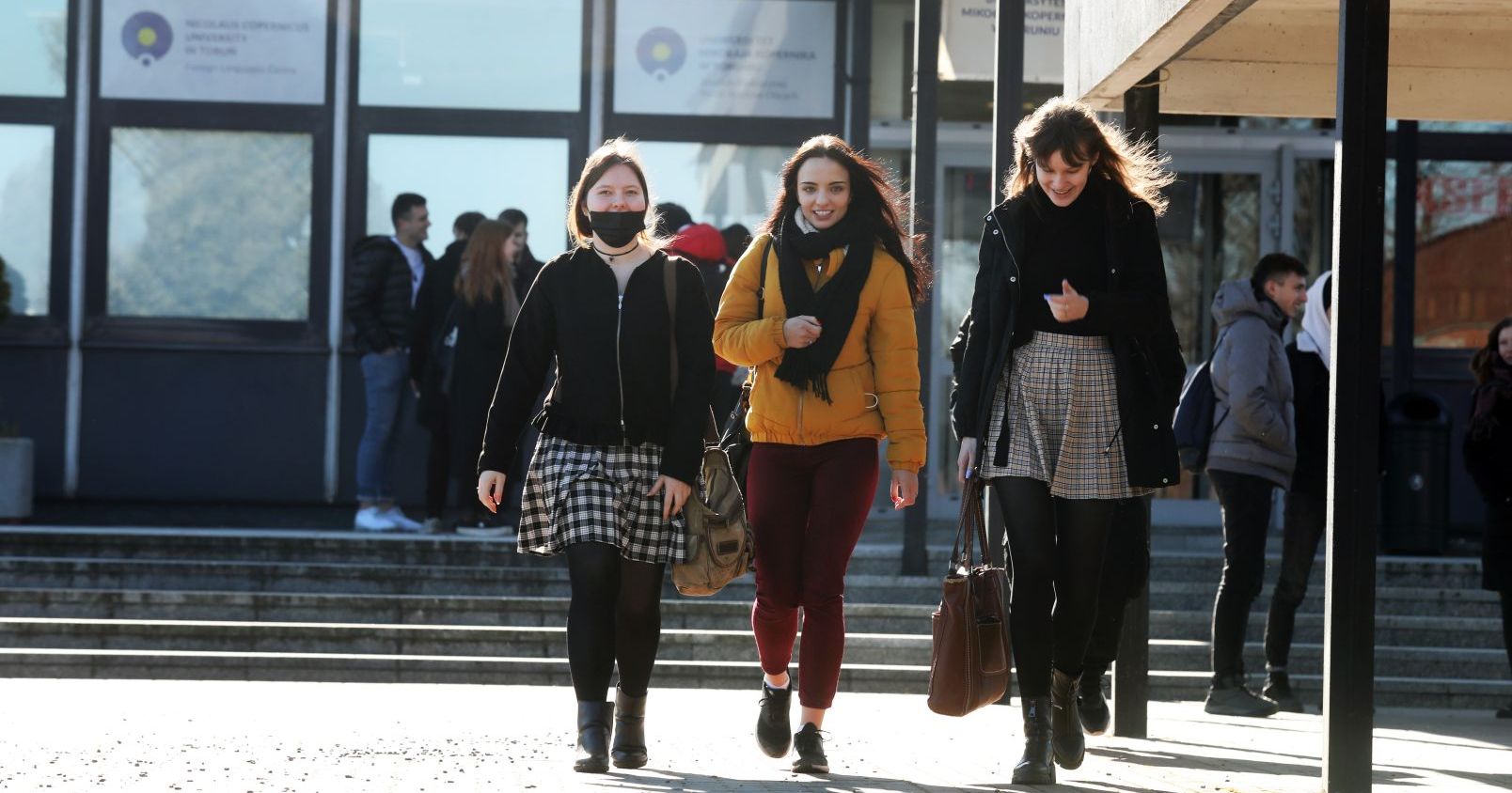  3 studentki idą chodnikiem w miasteczku akademickim