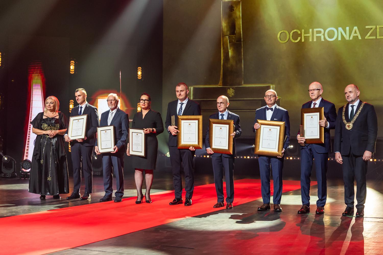 Laureaci nagr&oacute;d marszałka i wyr&oacute;żnieni pozują z dyplomami do zdjęcia na scenie