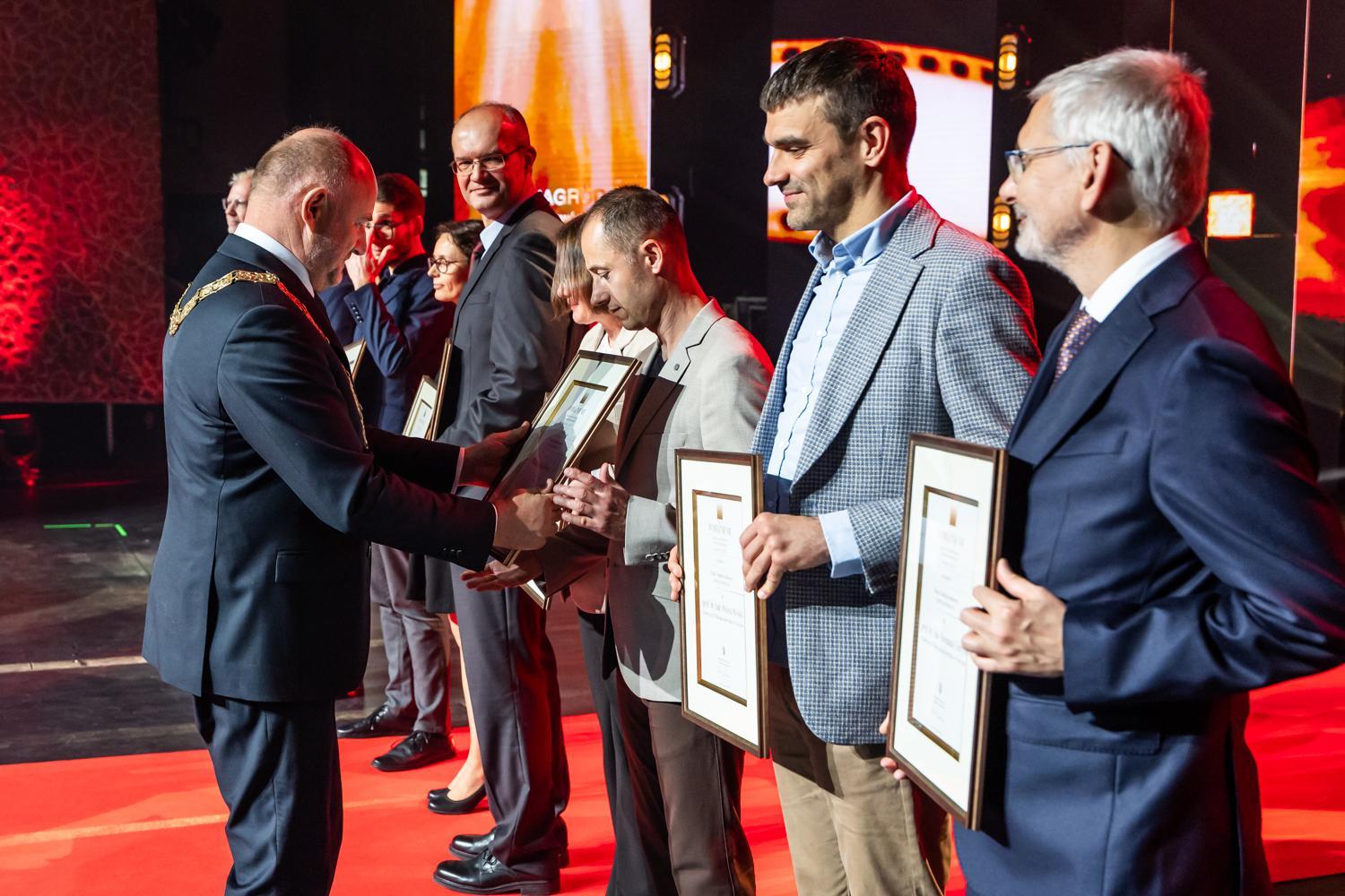 Marszałek wręcza nagrody zespołowi prof. Wcisło, wszyscy stoją w rzędzie na scenie