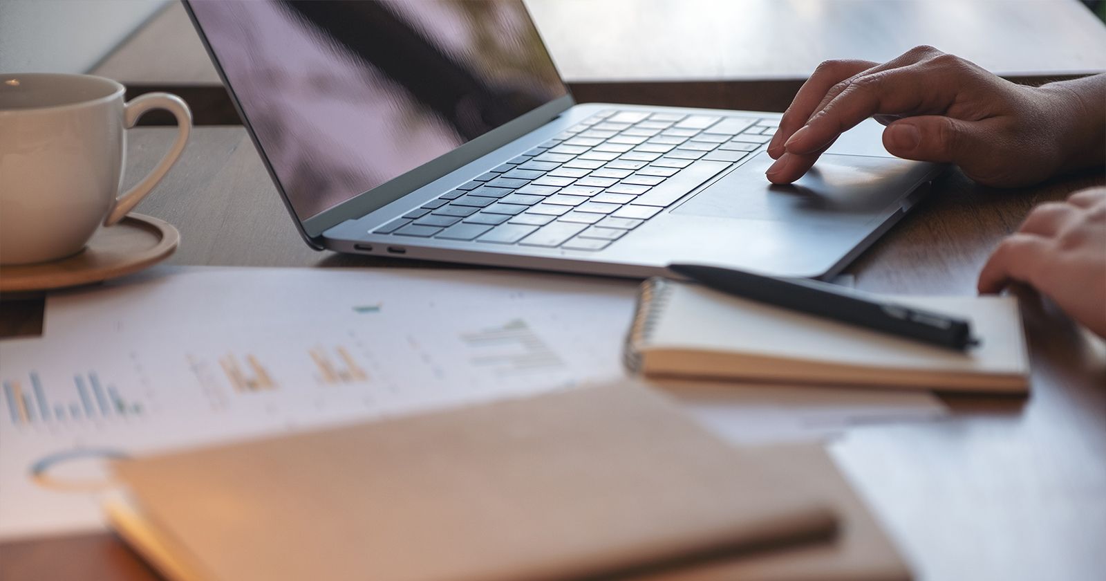 W tegorocznej edycji badaczkom i badaczowi z UMK przyznano jedną nagrodę i trzy wyróżnienia Zdjęcie biurka, na którym leżą różne notatki, notes i filiżanka. Na biurku stoi także laptop i widoczna jest dłoń osoby korzystającej z touchpada.