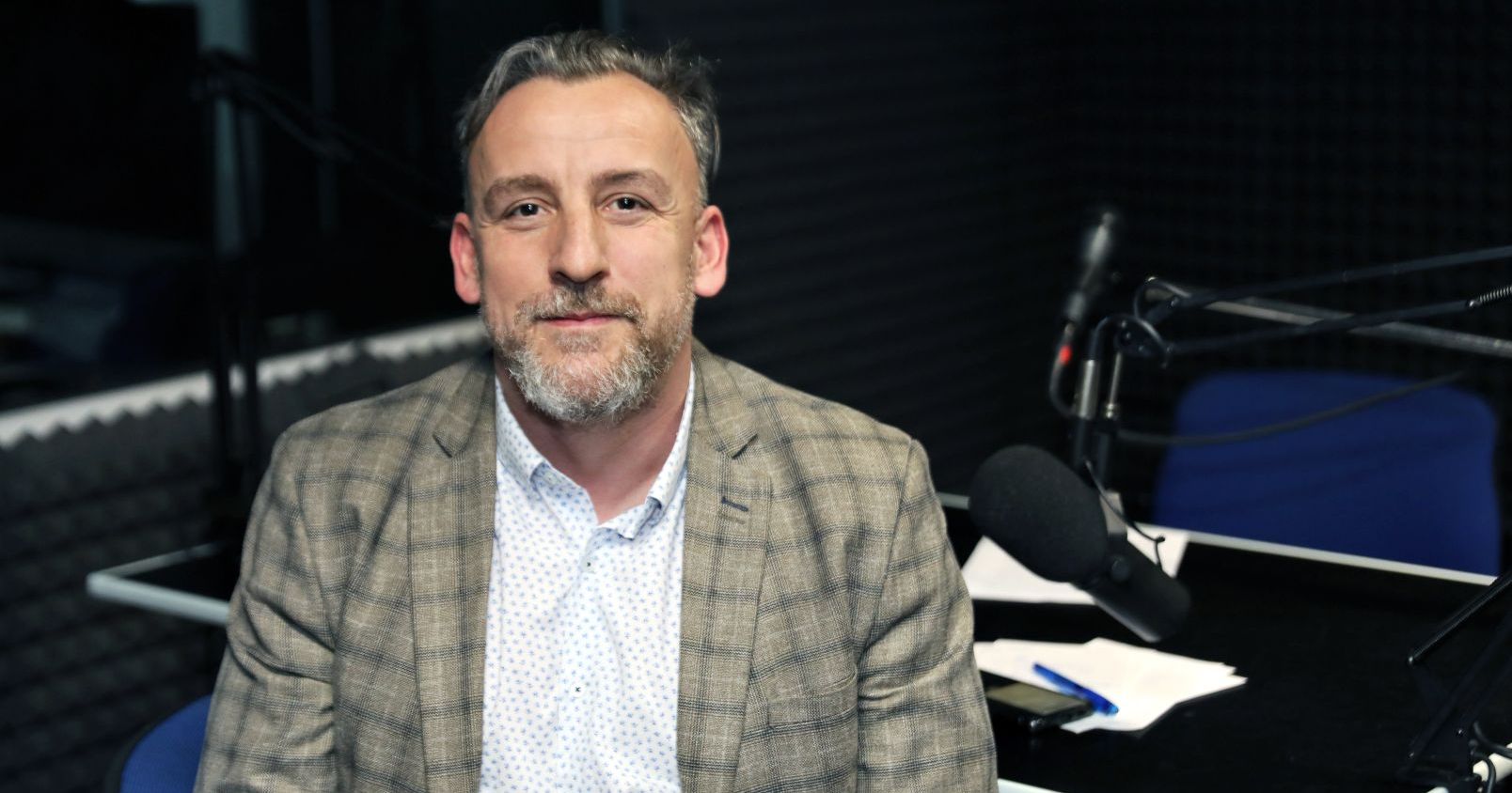 Audycji dr. Patryka Tomaszewskiego będzie można posłuchać w każdy czwartek na antenie Radia Sfera, a potem także w serwisie Spotify Zdjęcie portretowe dr. Patryka Tomaszewskiego. W tle widać elementy studia nagraniowego - wygłuszone ściany i mikrofon radiowy