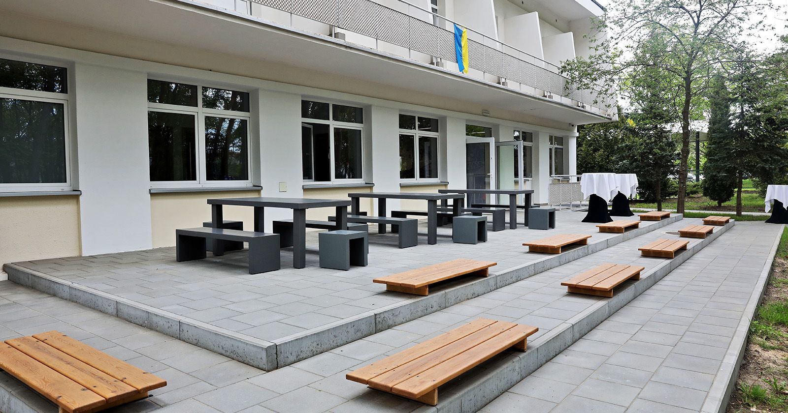  Przestrzeń rekreacyjna z ławkami i stołami przed budynkiem Instytutu Psychologii