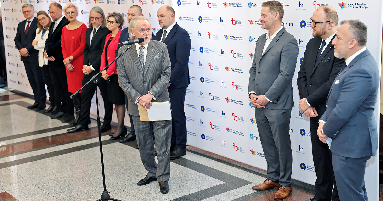 Rektor UMK przy mikrofonie, za nim zaproszeni goście: prezydent miasta, marszałek, wojewoda oraz przedstawiciele władz UMK