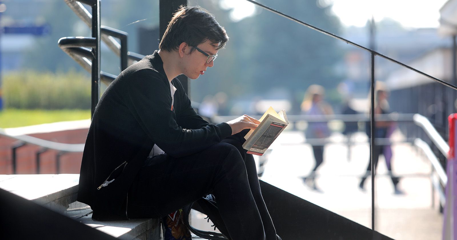  Osoba siedząca na schodzach i czytająca książkę