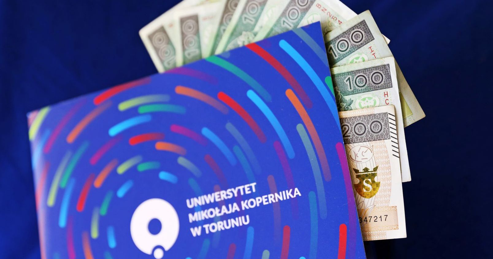  Papierowe banknoty w niebieskiej teczce z logo UMK