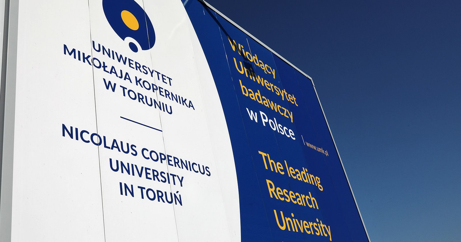  Tablica z logo UMK i napisem "Wiodący Uniwersytet badawczy"