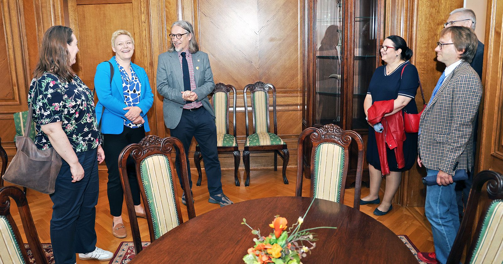 Sześć osób stoi w półkolu w zabytkowym wnętrzu budynku Collegium Maximum UMK
