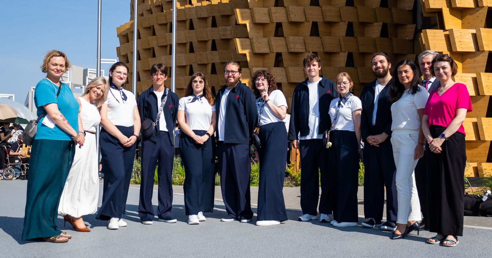 W czerwcu w ramach wizyty monitorującej naszych studentów w Osace odwiedziły dr Marcelina de Zoete-Leśniczak z Wydziału Humanistycznego i Anna Prykanowska z Działu Międzynarodowych Partnerstw i Mobilności Edukacyjnej Grupa kilkunastu osób, w tym studentów UMK, stoi przed okazałym drewnianym budynkiem Pawilonu Polski na EXPO